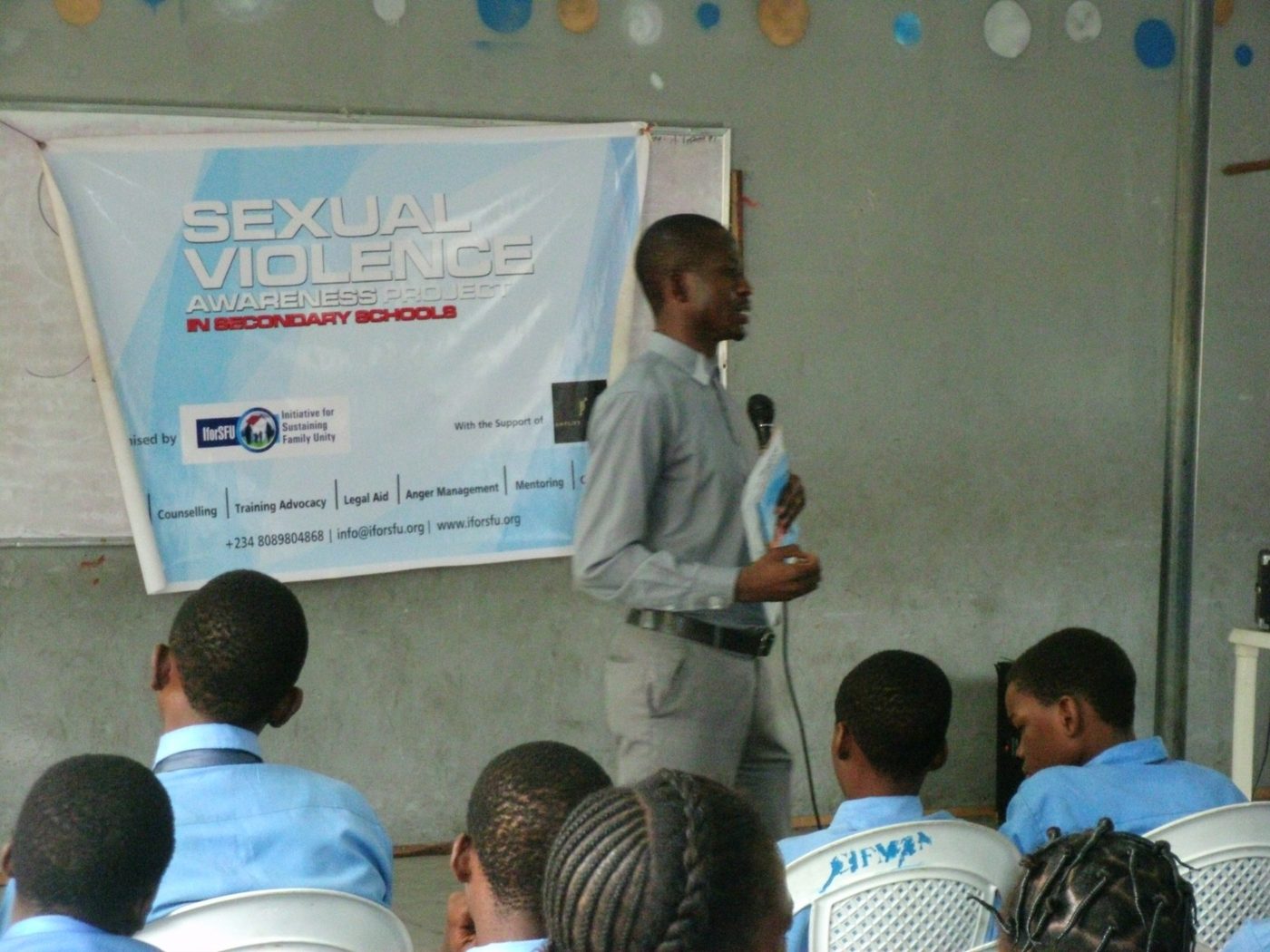 An IforSFU facilitator leading a Sexual Violence Awareness session beneath the project banner in a Lagos secondary school, 2016