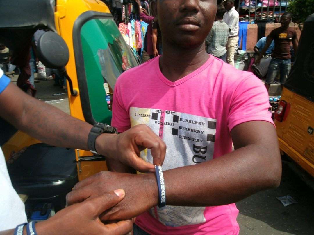 A reflective campaign wristband being fitted at the awareness stand, Tejuosho Market.